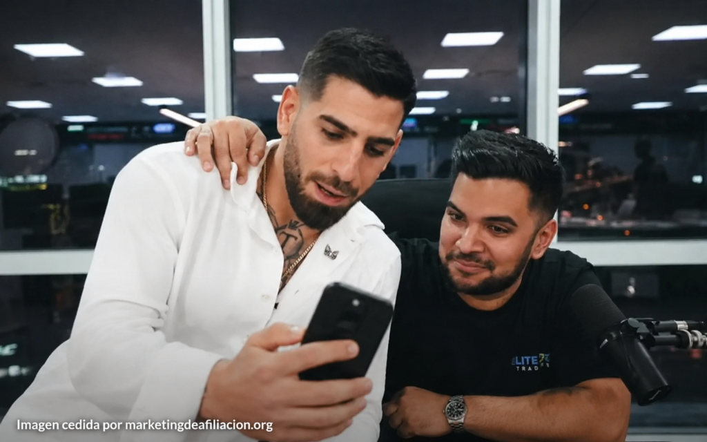 Pako Thawani junto a Ilia Topuria revisando un móvil en una oficina, imagen cedida por marketingdeafiliacion.org para reseña de Master Élite de Trading